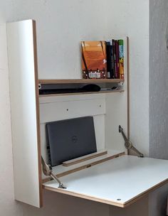 a white desk with a laptop on it and bookshelf in the back ground