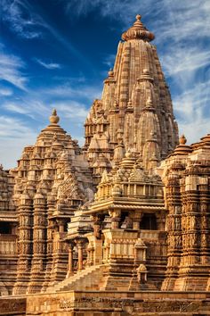 an intricately carved temple with many pillars and towers in the background, under a blue sky