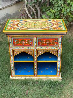 an ornate painted wooden cabinet in the grass