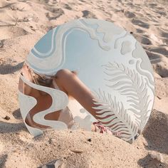 a woman's reflection in a circular mirror on the sand at the beach,