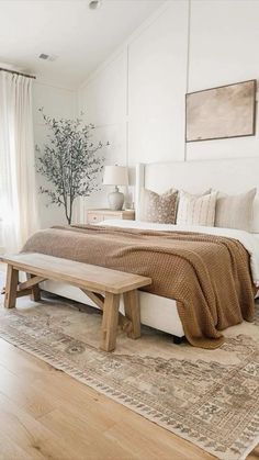 a bedroom with a large bed and wooden bench in the corner, along with a rug on the floor