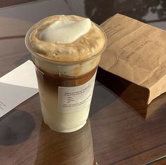 a cup of coffee sitting on top of a table next to a brown paper bag