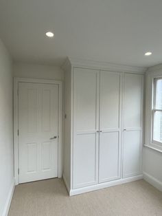 an empty room with white cupboards and carpeted flooring is pictured in this image