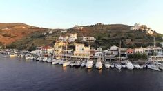 there are many boats that are docked in the water near some buildings and hills on top of a hill