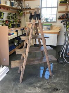 a wooden step ladder in a garage with tools on the floor and shelves behind it