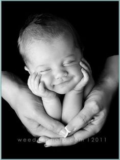 a black and white photo of a baby being held by two hands