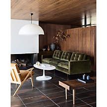 a living room filled with furniture and a fire place under a ceiling fan on top of a wooden paneled wall