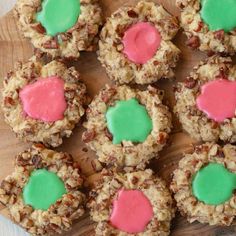 cookies with pink and green frosting are arranged on a wooden board, ready to be eaten