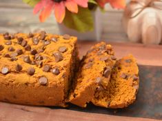 two slices of pumpkin bread with chocolate chip toppings on a cutting board next to a flower vase