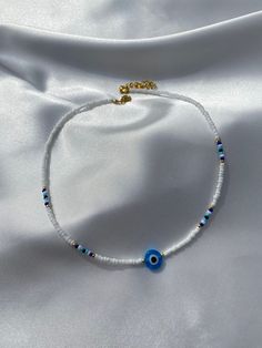 Nazar Evil Eye Choker with white and blue rocailles pearls. 💙 Quantity: 1x Nazar Evil Eye Chocker Size: Beads: 2-3 mm, Nazar Evil Eye: 10 mm If you have any further questions, please do not hesitate to contact me by message or even via Instagram (@boncuk.dream). Thank you and stay healthy! White Evil Eye Beaded Necklace, White Pearl Beaded Bracelets With Heart Beads, Evil Eye Bead Bracelet, White Beaded Necklaces With Heart And Round Beads, White Beaded Necklace With Heart And Round Beads, Handmade White Heishi Beaded Bracelets, Handmade White Heishi Beads Bracelets, White Tiny Beaded Necklaces For Jewelry Making, White Beaded Necklaces With Heart Beads And Adjustable Fit