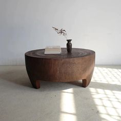 a wooden table with a book on it and a vase sitting on top of it