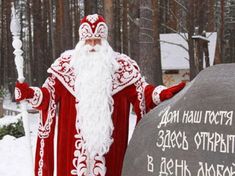 a man dressed in red and white standing next to a stone with writing on it