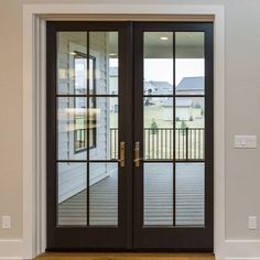 an empty room with two double doors and wood flooring on one side, looking out onto the front yard