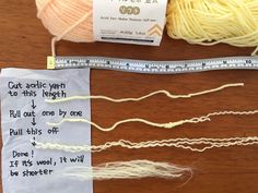 two skeins of yarn and a ruler on a table with words written on them