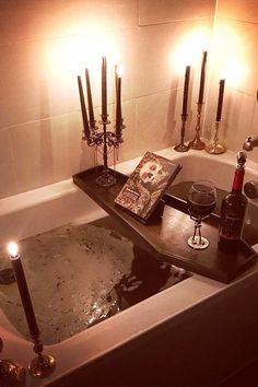 a bathtub with candles and wine in the tub, next to it is a book