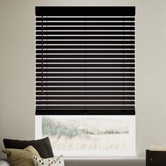 a living room with a couch and window covered in black blind shades on the windowsill