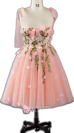 a pink dress with flowers and leaves on the front, sitting on a mannequin