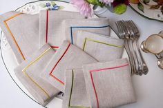 the table is set with napkins, silverware and flowers in vases on it