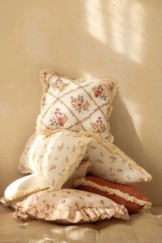 three pillows stacked on top of each other in front of a wall with sunlight coming through the window