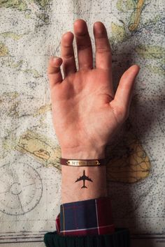 a person's arm with a plane tattoo on it and a map in the background