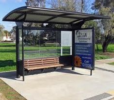 a bus stop with a bench in front of it and a sign on the side