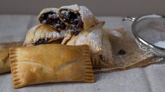 some pastries are sitting on a table next to a strainer