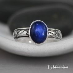 This striking Blue Sapphire Ring features a 10 mm x 8 mm oval cabochon of lab grown Blue Sapphire that has been securely set in a fine silver bezel. Traditionally, people attributed to Blue Sapphire the power to bring harmony between lovers as well as peace between adversaries. We are happy to create this beautiful ring for you in a variety of ring sizes, finish options, or in any of the stone choices shown in the images above. The band of this Sterling Silver ring features an Art Deco inspired Oval Cabochon Sapphire Promise Ring, Sapphire Jewelry With Oval Cabochon For Gift, Sapphire Cabochon Rings For Gifts, Classic Oval Blue Moonstone Ring, Celestial Oval Cabochon Rings, Blue Sapphire Ring Oval Cabochon, Handmade Blue Celestial Rings, Handmade Celestial Blue Rings, Blue Celestial Moonstone Ring As Gift