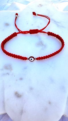 Embrace protection and style with our handcrafted Red Thread Bracelet featuring a stunning Evil Eye charm. This bracelet is designed to ward off negative energies and bring you peace of mind. The vibrant red thread symbolizes strength and vitality, making it a perfect accessory for everyday wear. Crafted with care, the Evil Eye charm is made from durable, water-resistant metal, ensuring that you can wear it all day, every day, without worry. Whether you're at the beach, working out, or enjoying Traditional Red Bracelets For Meditation, Red Spiritual Bracelet For Good Luck, Spiritual Red Bracelet For Good Luck, Red Round Bracelets For Meditation, Adjustable Red Beaded Bracelets For Meditation, Red Spiritual Bracelets For Friendship, Red Spiritual Friendship Bracelets For Good Luck, Traditional Hand Wrapped Red Bracelets, Traditional Red Hand Wrapped Bracelets