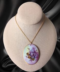 This 1970's Floral hand painted artisan signed floral pendant is a gorgeous piece with beautifully vibrant colored detail. This rare pendant measures 2 1/2 x 1 3/4 inches and is in wonderful condition. The gold tone chain with pendant measures 12 1/4 inches in length. It presents a rich and elegant statement to any ensemble. Vintage Hand Painted Round Pendant Necklace, Vintage Hand Painted Pendant Jewelry, Vintage Hand Painted Round Jewelry, Vintage Round Hand Painted Jewelry, Vintage Hand Painted Necklace As Gift, Hand Painted Vintage Necklace As Gift, Hand Painted Vintage Necklace For Gift, Vintage Hand Painted Necklaces For Gift, Vintage Hand-painted Pendant Necklace