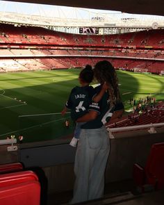 two people standing in the stands at a soccer stadium with their arms around each other