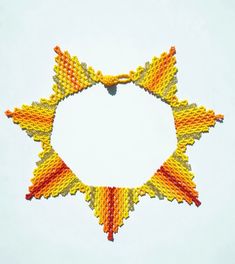 an orange, yellow and red beaded star with a white circle in the middle