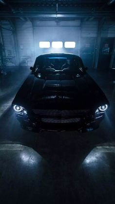 a black car in a dark garage with lights on it's headlamps