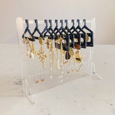 a rack with several pairs of earrings hanging from it's hooks on a marble countertop