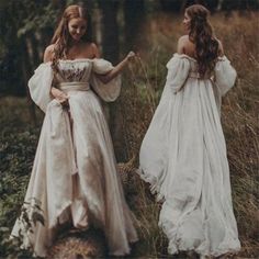 two women in white dresses walking through the woods