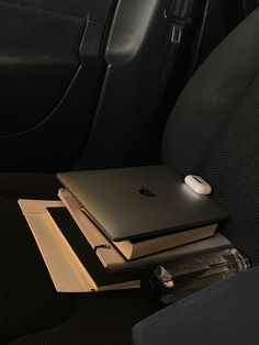 an apple laptop sitting on top of two books in the back seat of a car