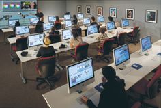 people are sitting at desks with computers in front of them and on the wall