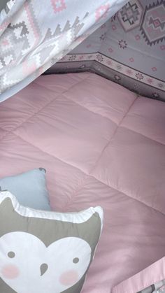 a child's bed with pink comforter and pillows on it, next to a stuffed animal pillow