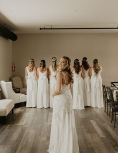 a woman standing in front of a group of bridesmaids wearing white gowns