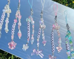 a bunch of necklaces that are on a blue table outside with flowers in the background