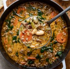 a spoon full of soup on top of a wooden table