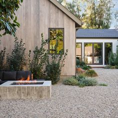 a fire pit in the middle of a gravel area next to a wooden building and trees