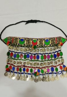 * This traditional classic necklace is an epitome of tradition. The tribal choker statement features three layers, each embellished with multicolour glass stones. * The style of the necklace is inspired by the Kuchi style of ornaments, as adorned with floral motifs and vintage coins dangling at the bottom. * The golden silver hues are complementing the vibrant glass stone inlays and elements at the top and bottom. The tribal necklace is a traditional fashion jewelry statement, festooned with met Traditional Adjustable Necklaces With Colorful Beads, Traditional Adjustable Necklace With Colorful Beads, Traditional Necklaces With Colorful Beads And Adjustable Fit, Handmade Multicolor Jewelry For Traditional Ceremonies, Traditional Beaded Festival Jewelry, Multicolor Bohemian Jewelry For Traditional Ceremonies, Traditional Jewelry For Festivals, Bohemian Jewelry For Ceremonial Festival, Bohemian Jewelry For Traditional Ceremonies