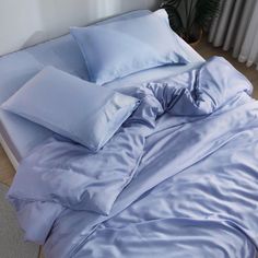 an unmade bed with blue sheets and pillows