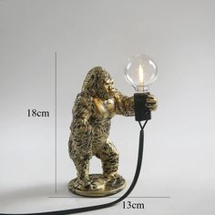 a gold gorilla lamp with a light bulb on it's side and measurements for the size