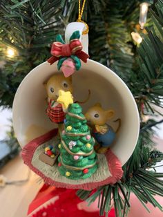 a christmas ornament hanging from a tree with two mice on it's side