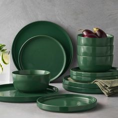 the green dishes are stacked on top of each other and have plates, cups, and bowls in them