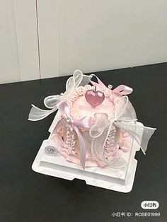 a cake in the shape of a heart on top of a black table with ribbon