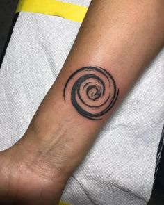 a person with a tattoo on their arm that has a spiral design in the middle