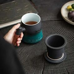 a person holding a coffee mug on top of a table