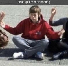 two people sitting on the ground with their hands in the air and one person standing behind them